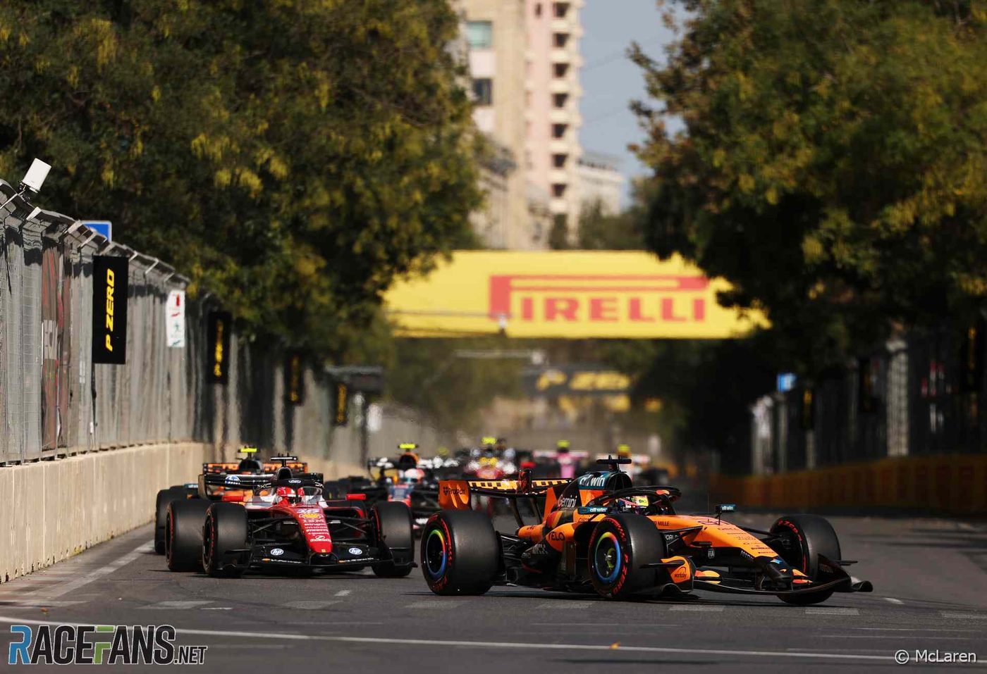 A McLaren leads a Ferrari and the pack along a tree-lined stretch of the Baku City Circuit