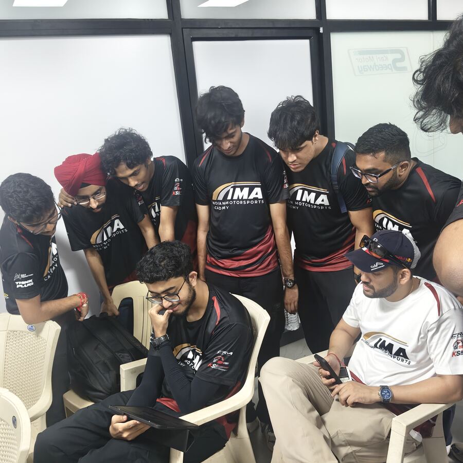 Group huddled around a laptop reviewing data indoors