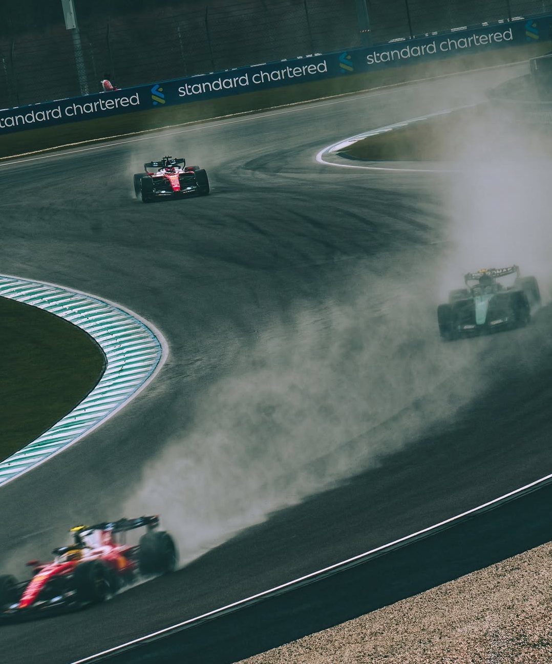 Two Ferraris and a Mercedes throw up spray on a drying Sepang track